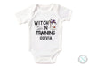 a white bodysuit with the words witch in training written on it